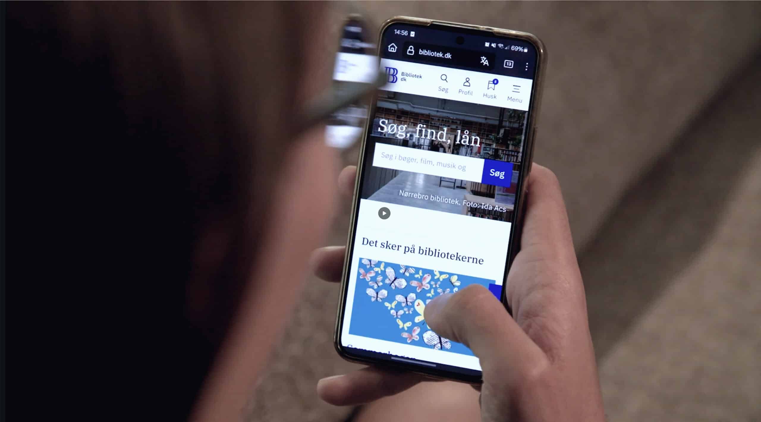Person ser på mobiltelefon med bibliotek.dk
