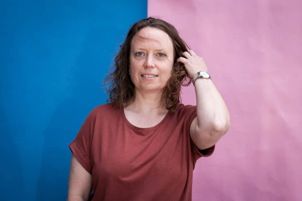 Portræt af Linda foran en blå og lyserød væg